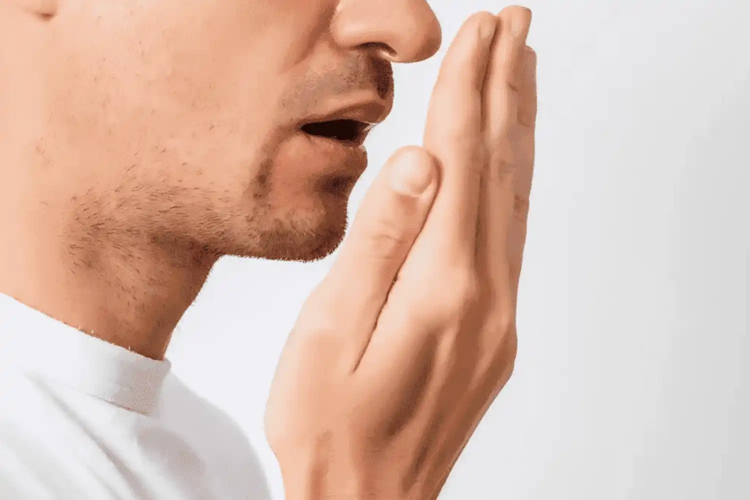 Man houdt hand voor zijn mond om te controleren of hij een slechte adem heeft